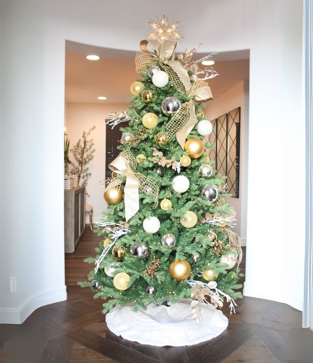 Elegant Christmas tree with gold and silver ornaments in a modern holiday living room.
