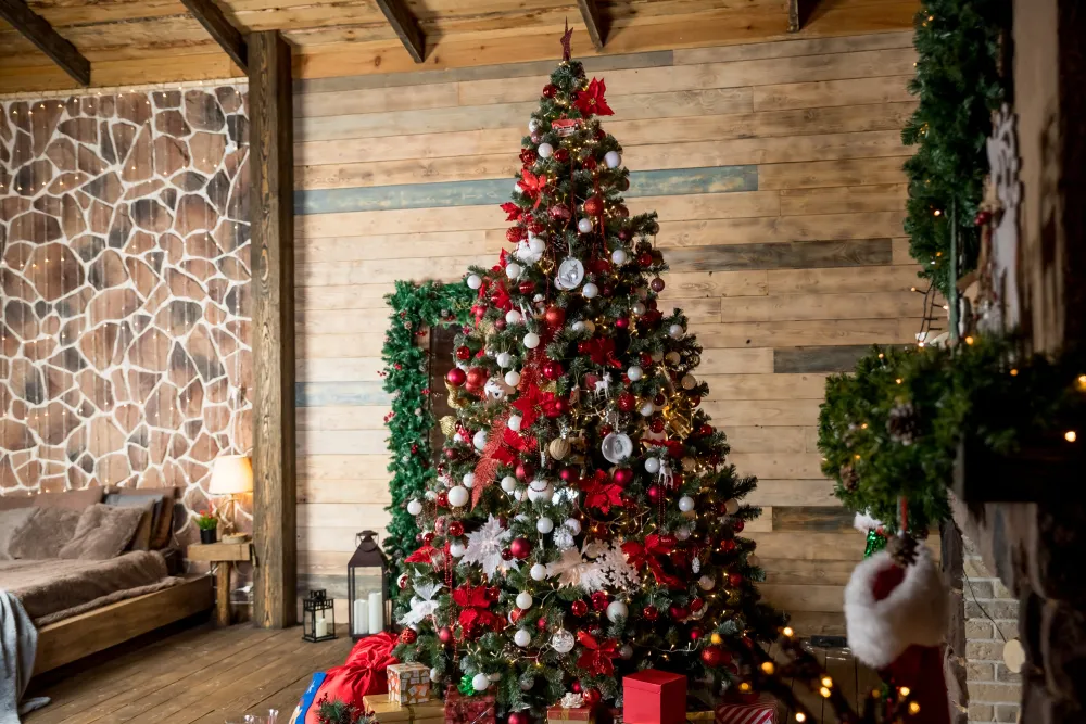 Warm and cozy indoor Christmas scene with a decorated evergreen tree, red and gold ornaments, white snowflakes, and colorful gifts under soft lighting.